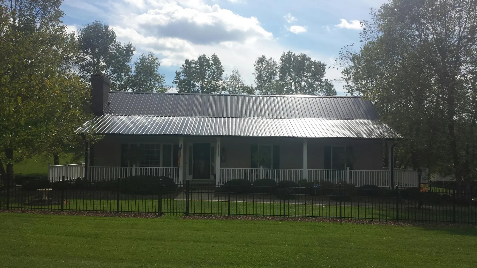 Gray metal roof on a brick ranch with a full width front porch — Gutter Guard Installation work by our crew in Gravity