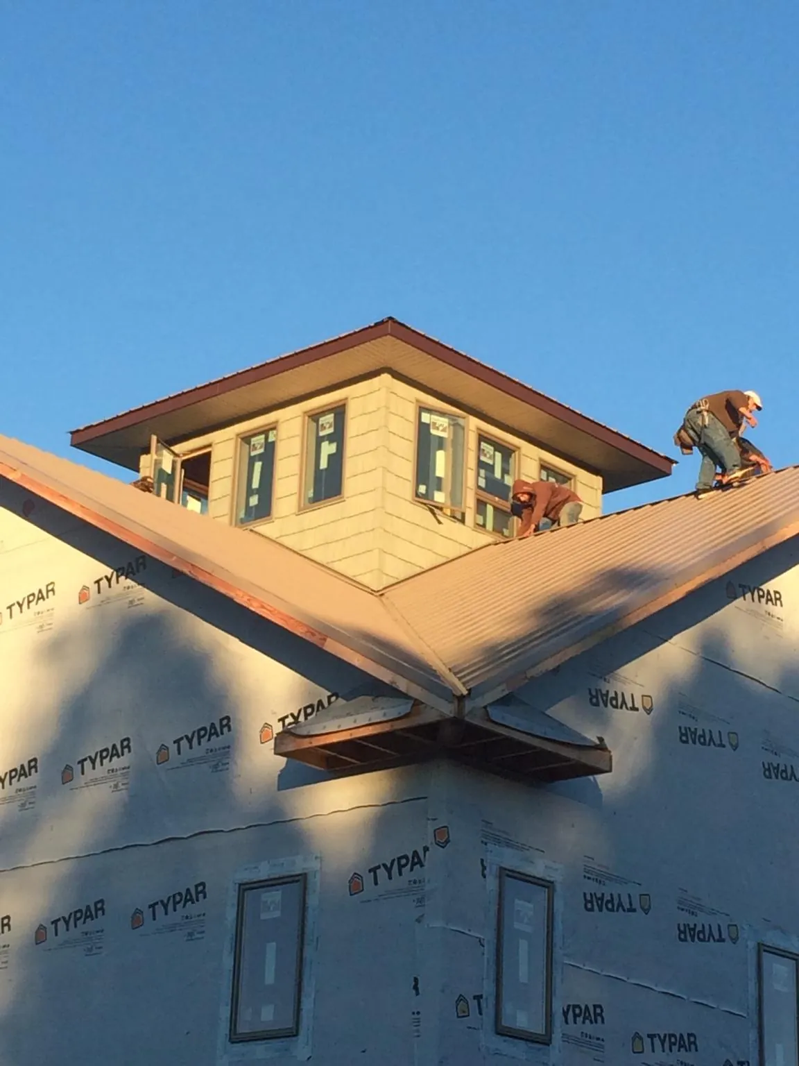 Roofers working around a rooftop cupola on a new metal roof at sunset — Roof Waterproofing in Gravity by Roofing Brothers